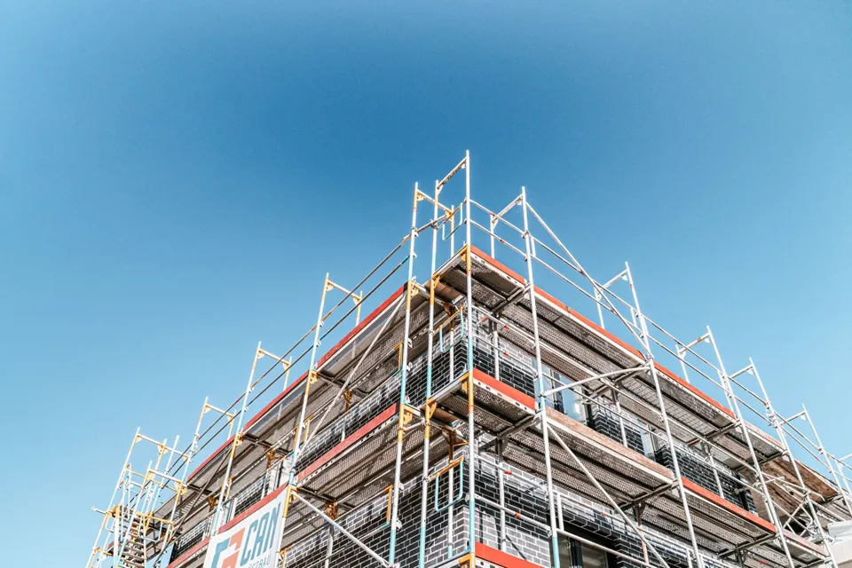 Gerüst an der Ecke eines Backsteingebäudes vor blauem Himmel