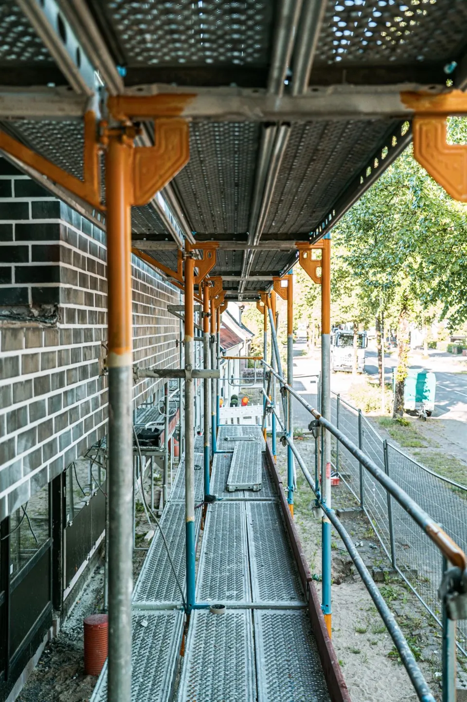 Blick entlang eines Gerüstgangs zwischen Fassade und Seitenschutz